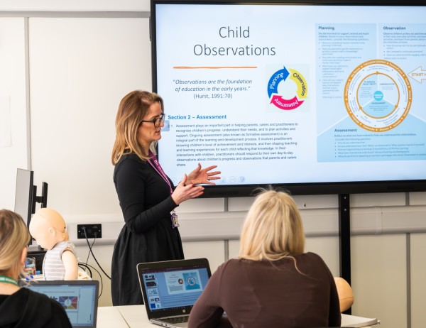 A Childhood Studies teacher is teaching in front of an interactive whiteboard.