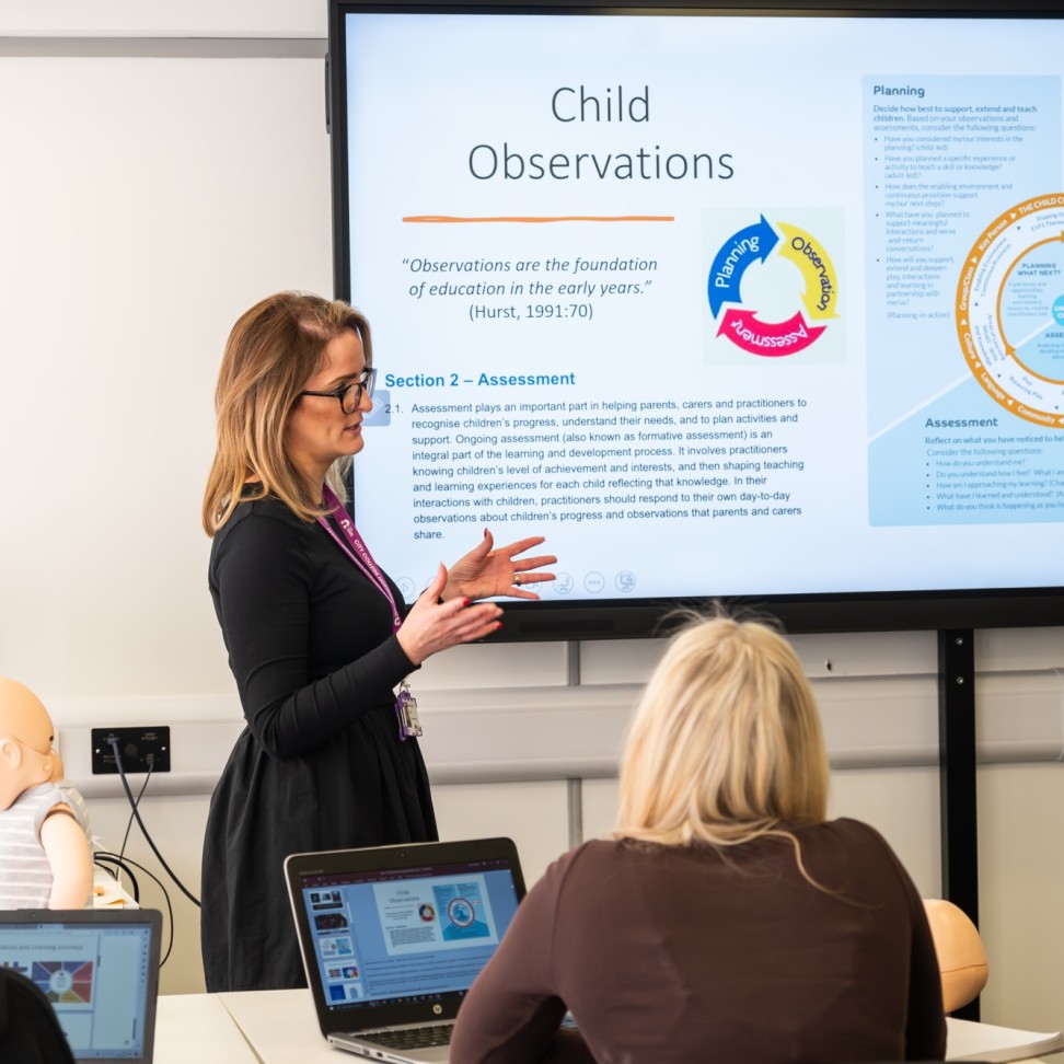 A Childhood Studies teacher is teaching in front of an interactive whiteboard.
